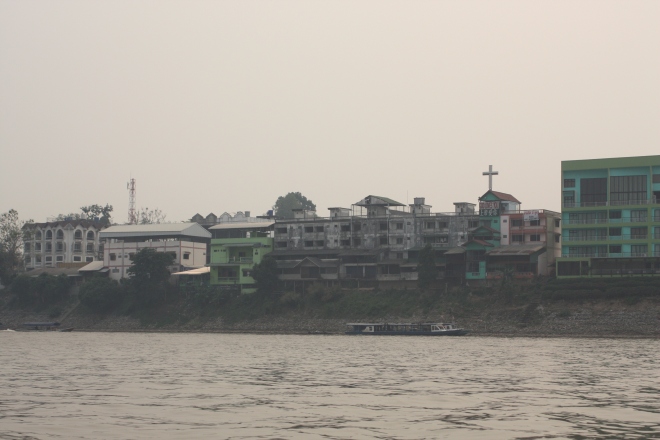 Buildings on the Thai side of the Mekong River. Note the large cross on one of them. A banner beneath it read "God loves you". 